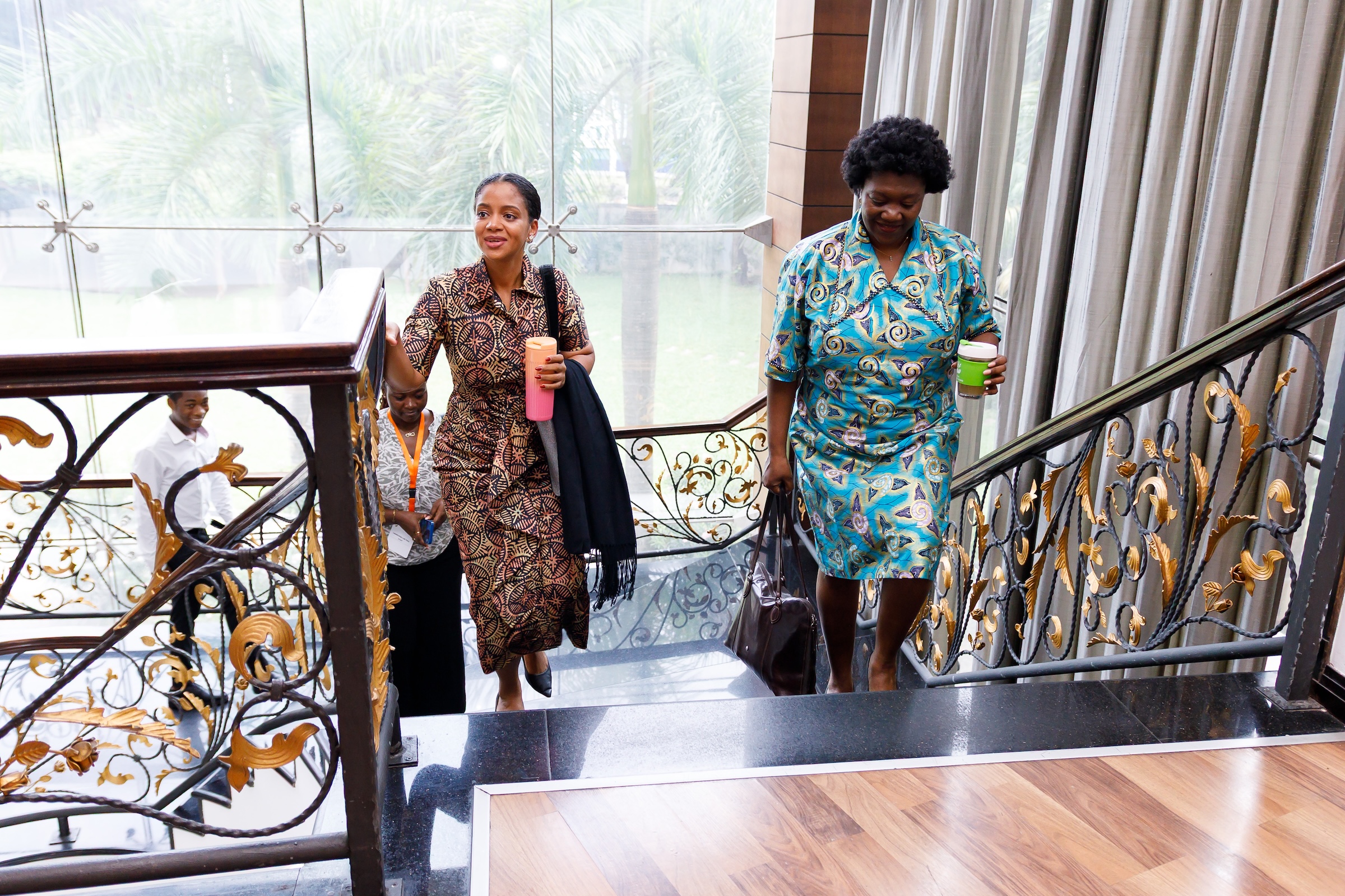 Two female participants arrive at a Leadership Lab Yetu convening, walking up a staircase at the event venue